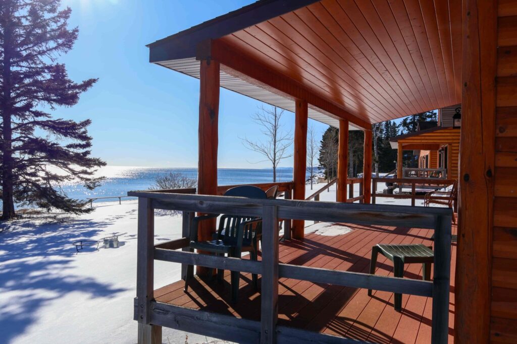 Snow-covered cabin deck at Ours Resort overlooking a frozen Lake Superior shoreline