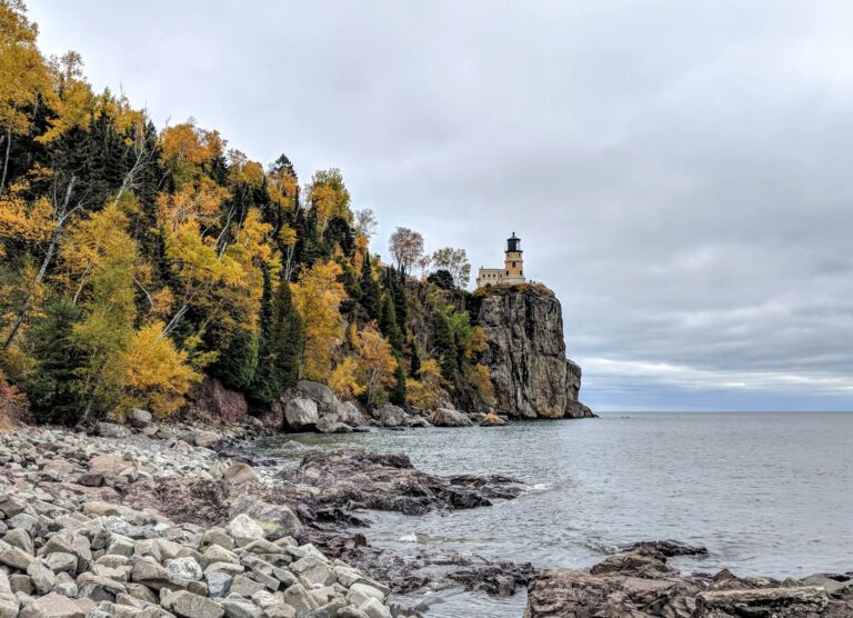 Split Rock Lighthouse on its cliff above Lake Superior with fall color along the shoreline